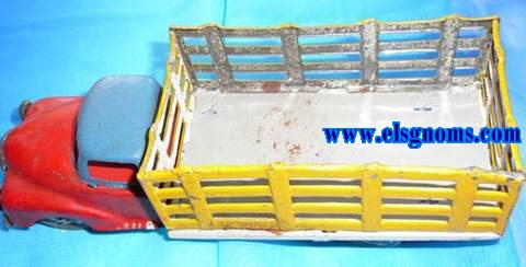 Camin fabricado en Portugal en hojalata embutida en prensa y troquelada. Cabina pintada en azul y cap en rojo. Soporte (suelo) pintado en gris.Caja troquelada en forma de reja pintada exterior en amarillo e interior blanco. Frontal y ruedas con restos de estao.