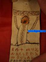 Kitab. Pieza realizada sobre pergamino completamente manuscrita con tinta negra y algunas en rojo, e ilustrado con 2 escenas estilizadas pintadas a mano en negro y rojo, y cuyo nombre kitab tanto en etiope como en rabe indica un amuleto mgico cristiano copto, as como la funcin de exorcizar a quien lo lleva, reproduciendo cuestiones morales, ticas y oraciones religiosas. Con invocaciones a los snatos y a la virgen
